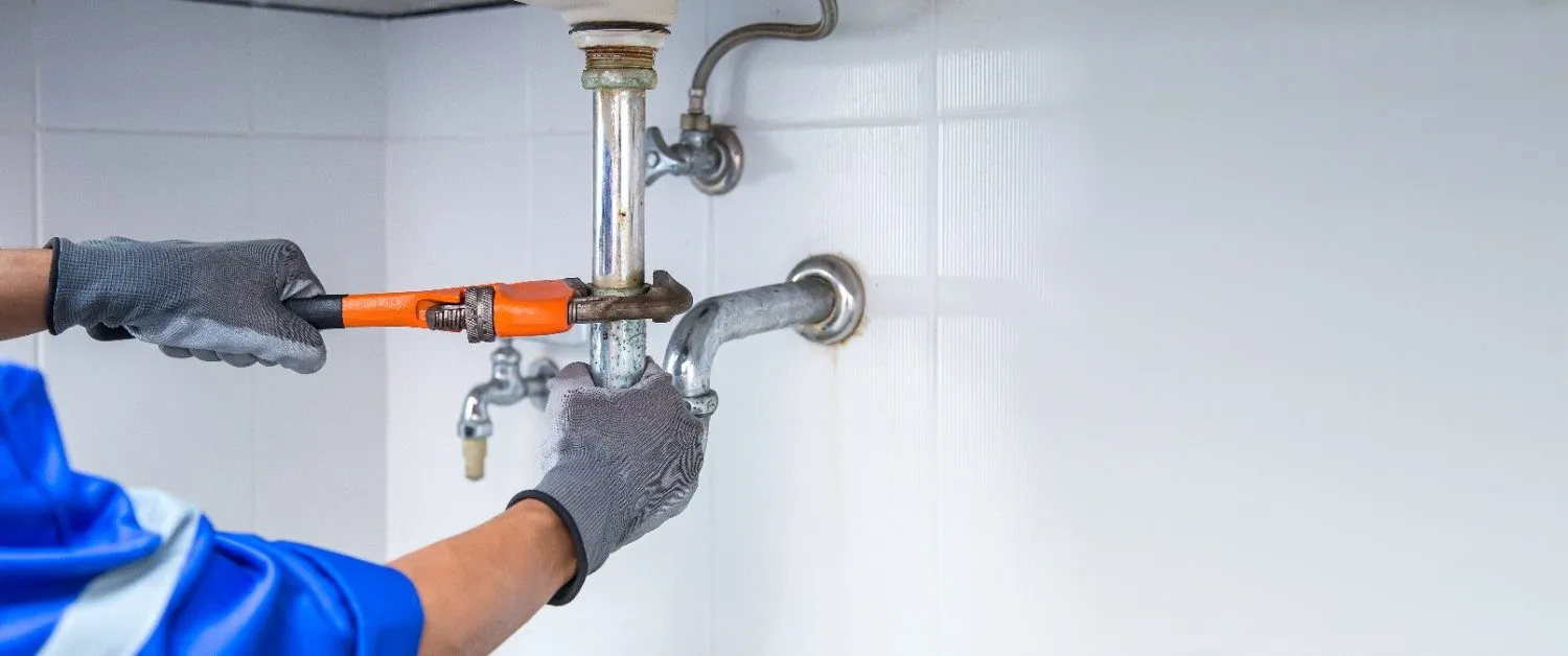 Plumber tightening a pipe fitting with a wrench